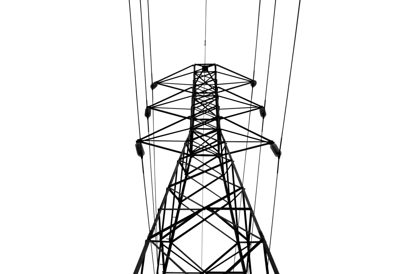 Torre de transmissão e seus cabos desenham linhas pretas contra o céu claro.