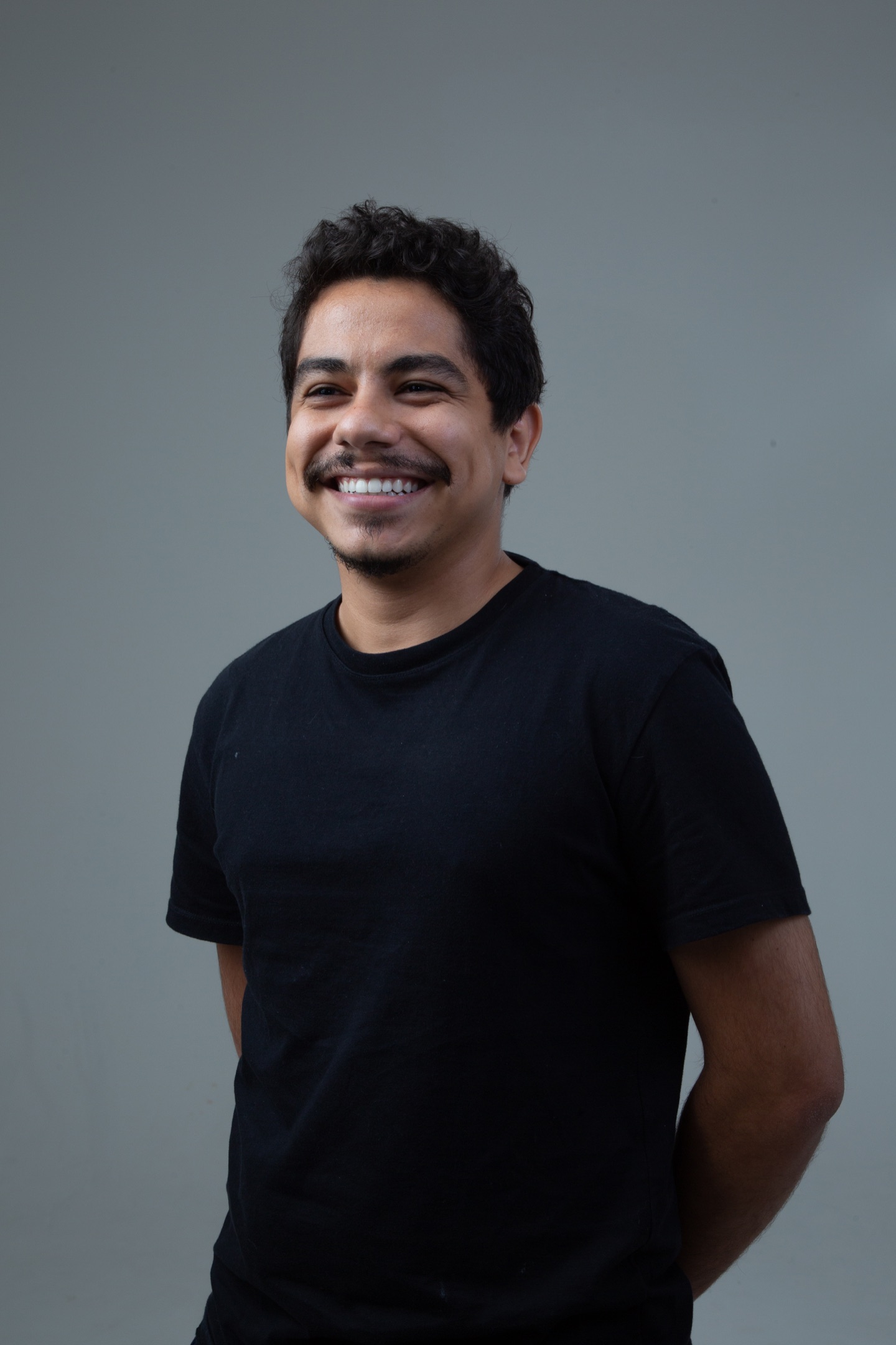 Gabriel Goes sorri para a câmera, de camiseta preta diante de um fundo cinza.