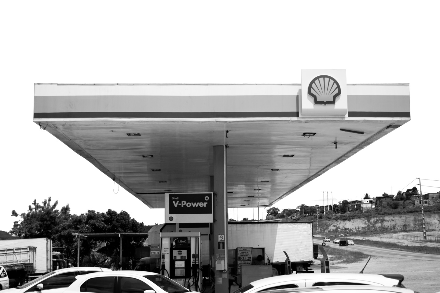 A cobertura de um posto de combustível vista de baixo, entre carros e estrada.